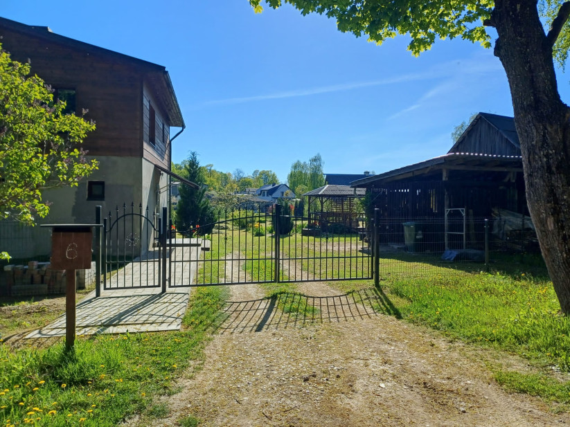  Divstāvu mājas aizmugure ar skatu uz dārzu. 