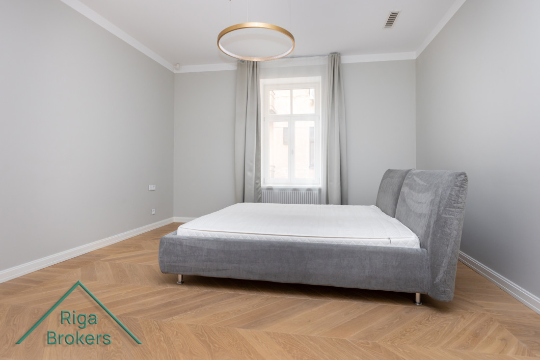 Bedroom with gray bed and window.