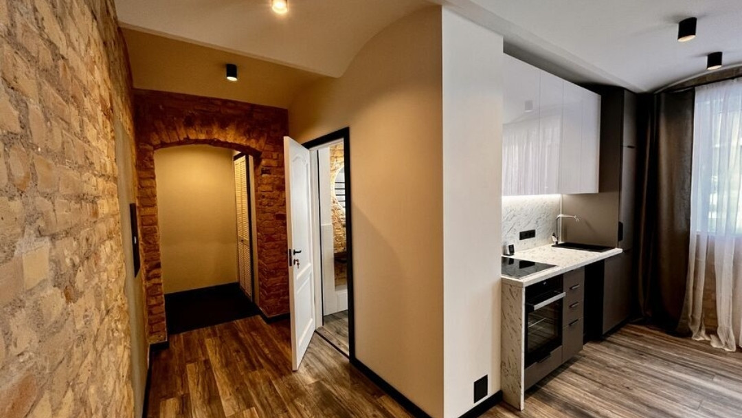 Small kitchen in a modern apartment with a brick archway.