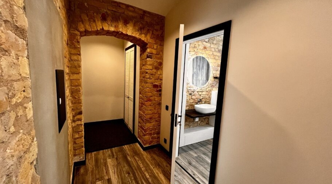 Masonry walls and wooden floors in a room with white doors.