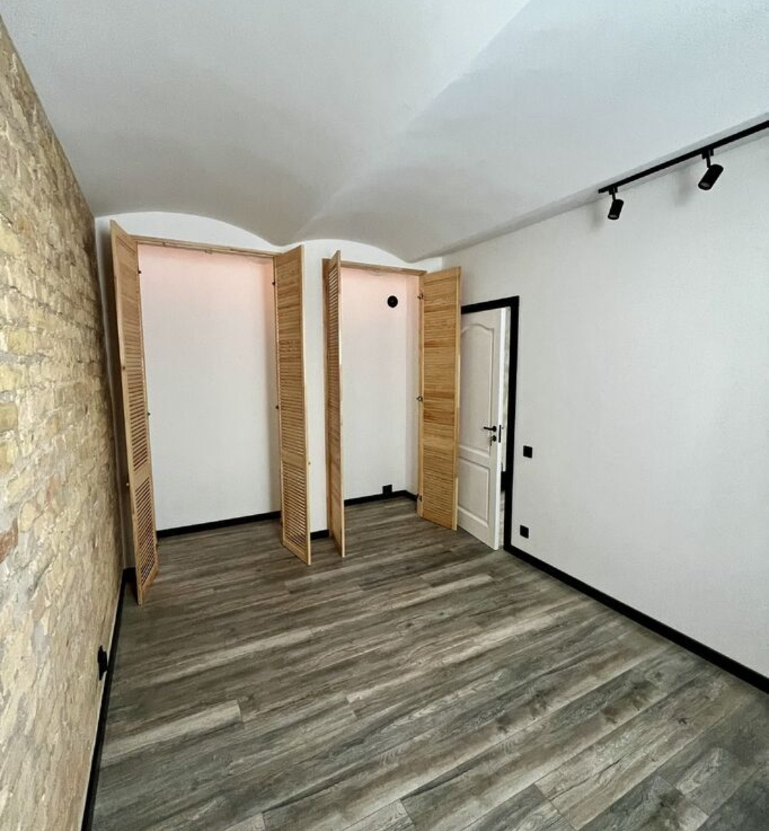 Empty room with brick walls and wooden floors.
