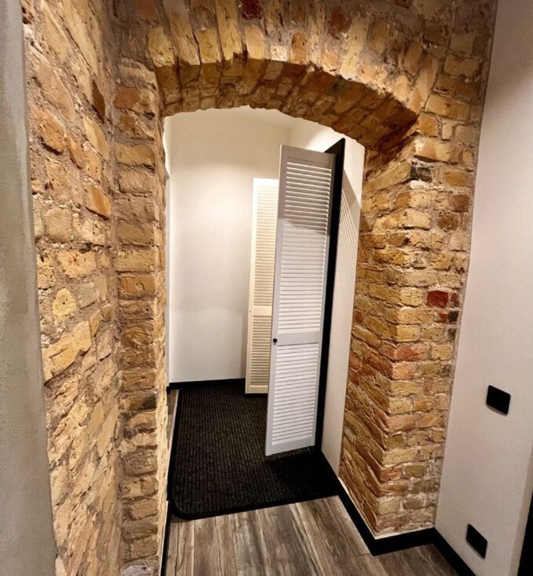 View of the entrance with a brick arch and white doors.