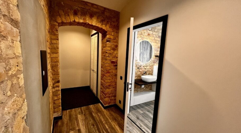 Masonry walls and wooden floors in a room with white doors.