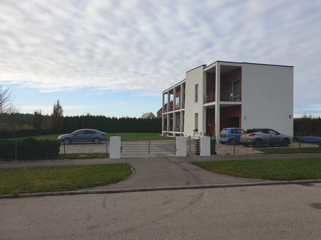 Modern two-story residential building with cars in front.