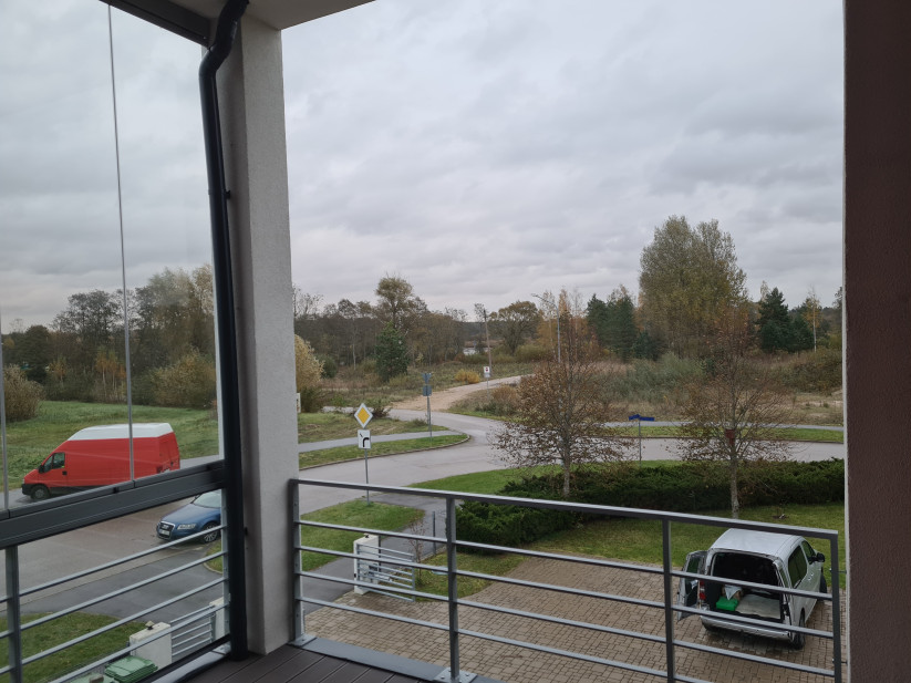 View from the balcony over a landscaped area and road.