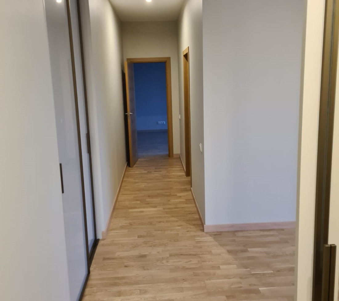 Long hallway with wooden doors and a mirror.