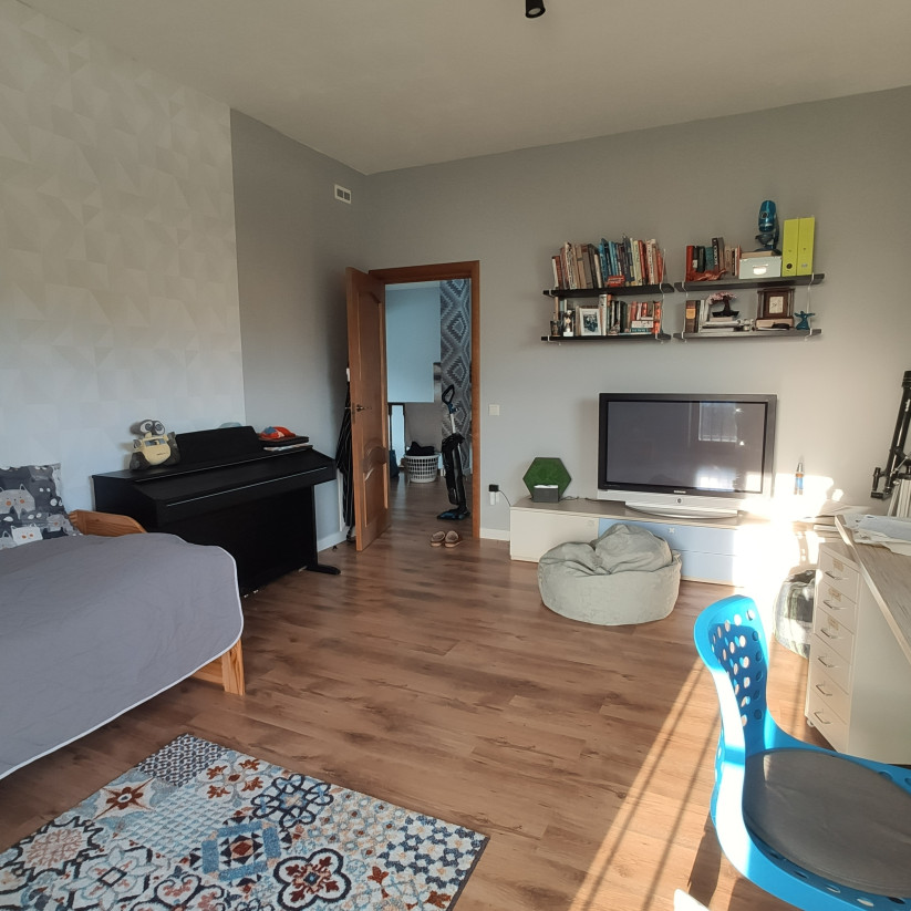 Mājīga dzīvokļa istaba ar klavierēm un TV.