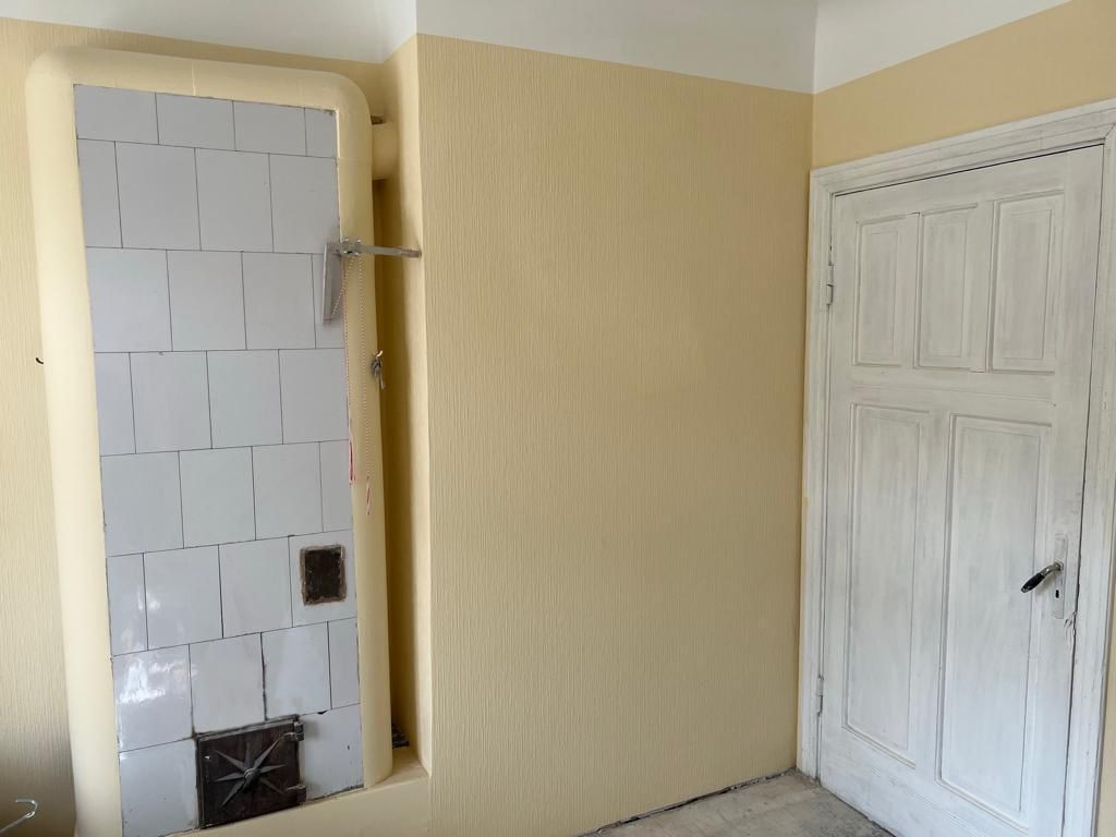 Bright room with a wall stove and a door.