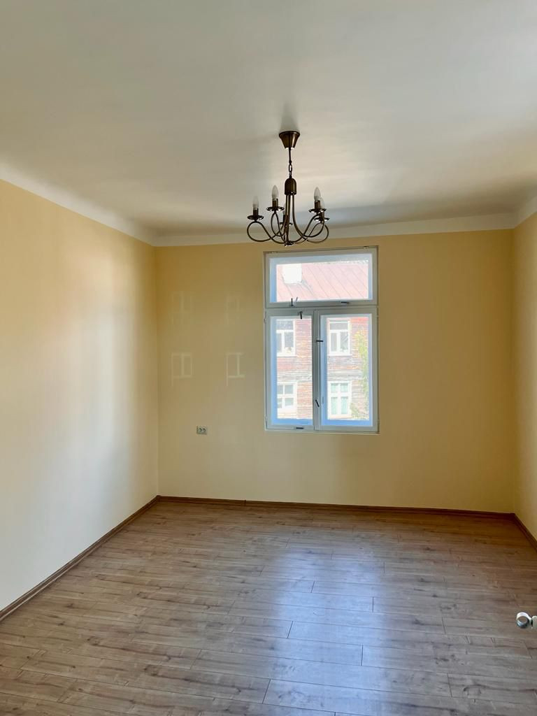 Spacious room with a chandelier and a window.