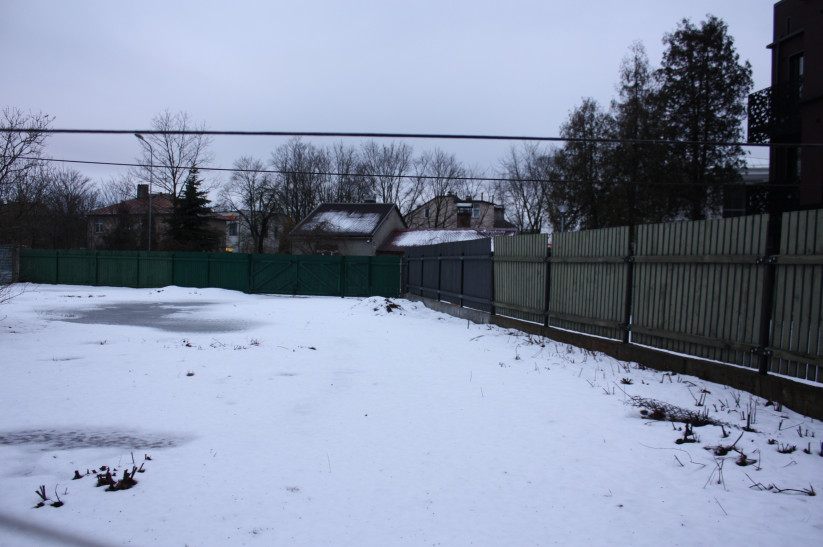 Snowy yard with view of buildings.