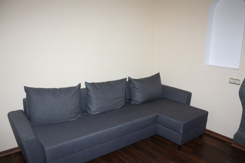 Gray sofa in room with wooden floor.
