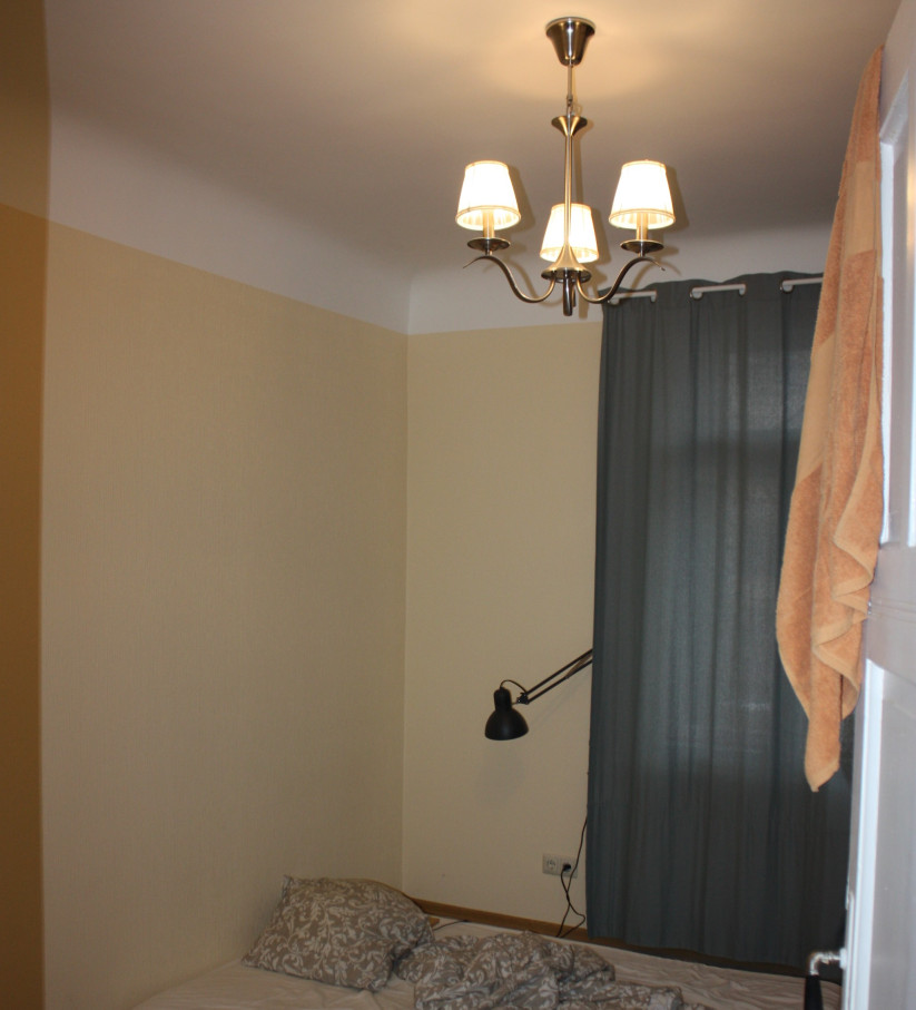 Small bedroom with bed and lamp.