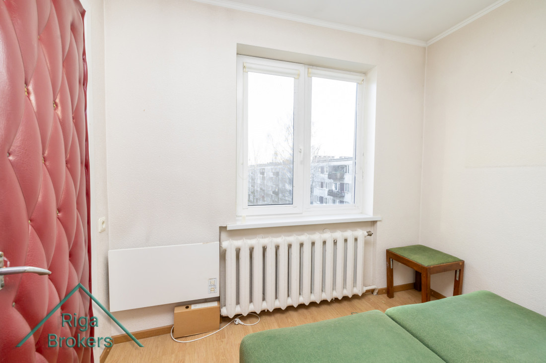 Gaiša istaba ar logu un radiatoru.