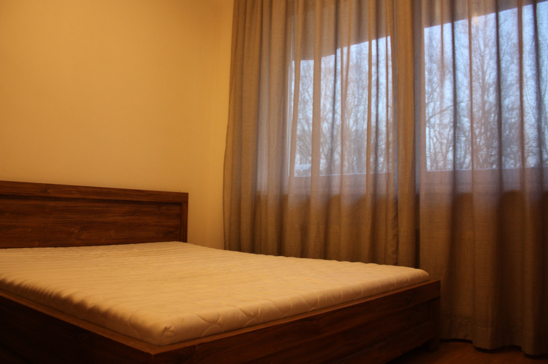 Bedroom with wooden bed and curtains.