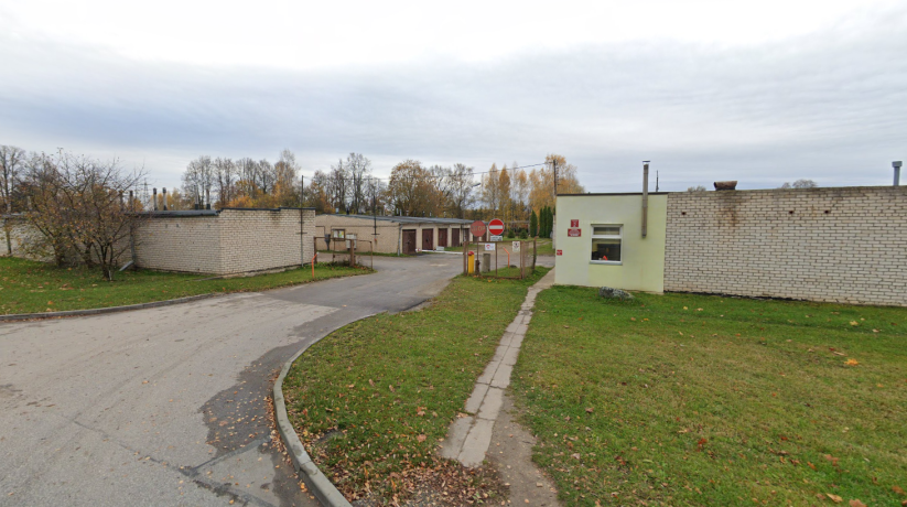 Priekšējais skats uz ēku ar piebraucamo ceļu un zaļām zonām
