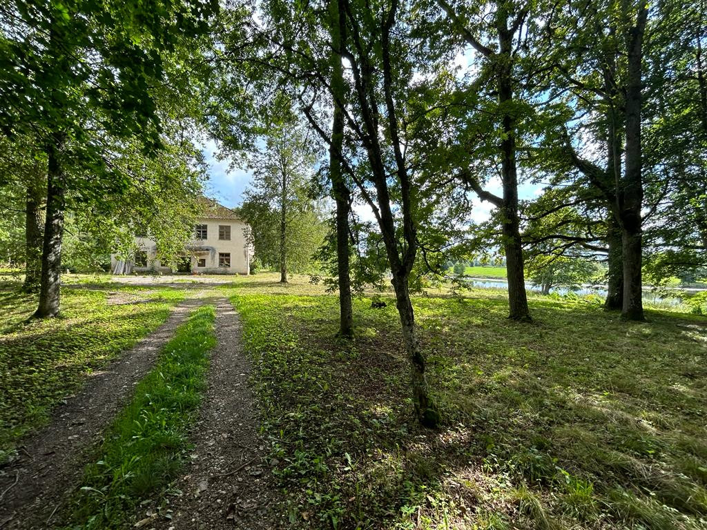 Veca ēka pie koku ieskautas takas.