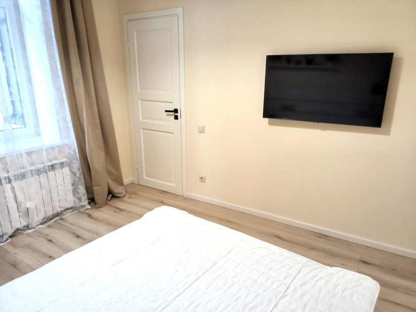 Bedroom with a wall-mounted TV and white bed.
