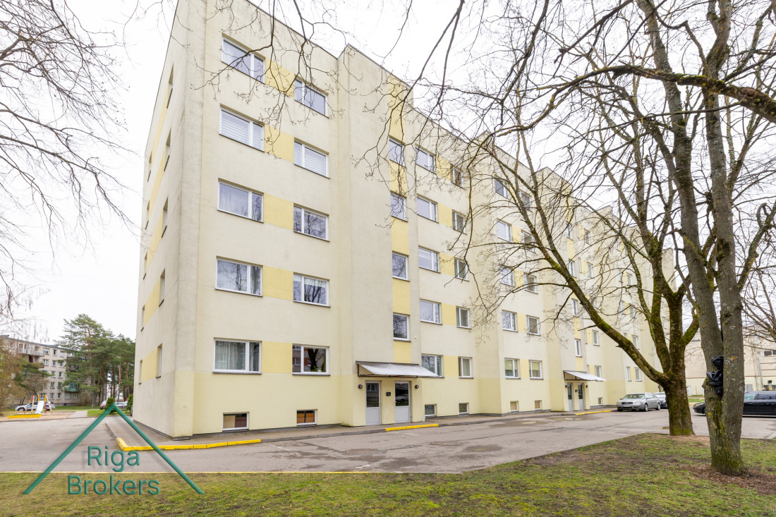 Daudzstāvu dzīvojamā ēka ar dzeltenām apdare.