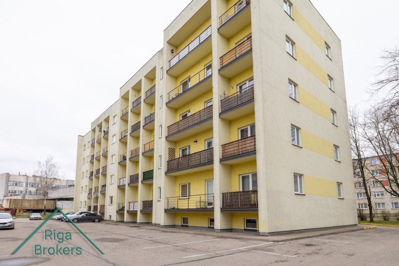 Dzīvojamā ēka ar balkoniem un dzeltenām sienām.