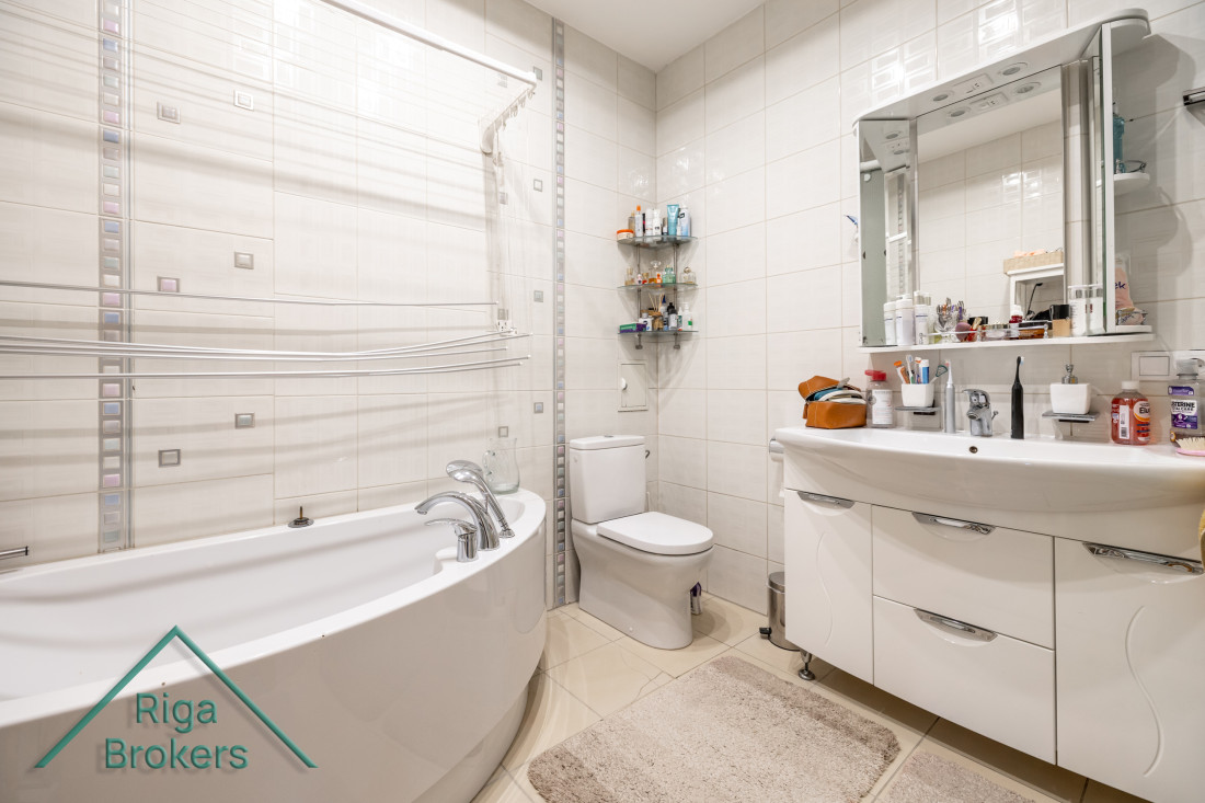 Spacious bathroom with corner bathtub and mirror.