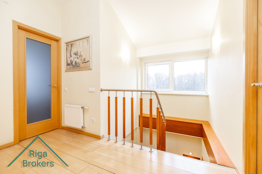 Light-filled hallway with wooden stairs.