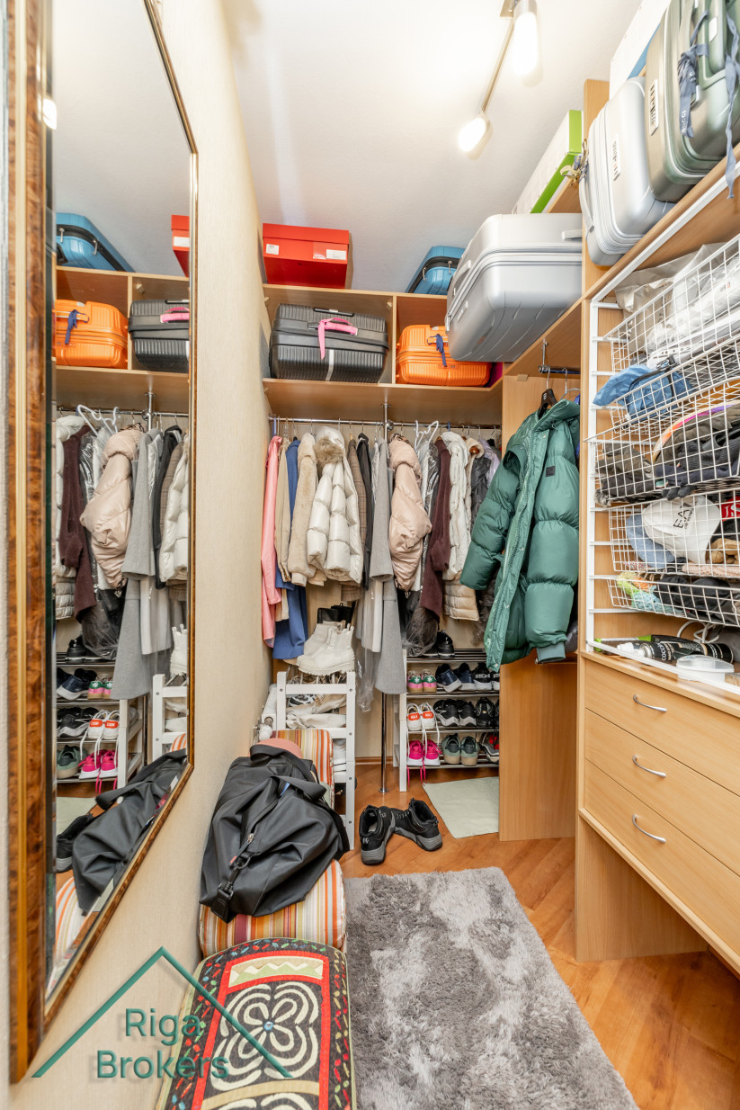 Hallway closet with clothes and luggage.