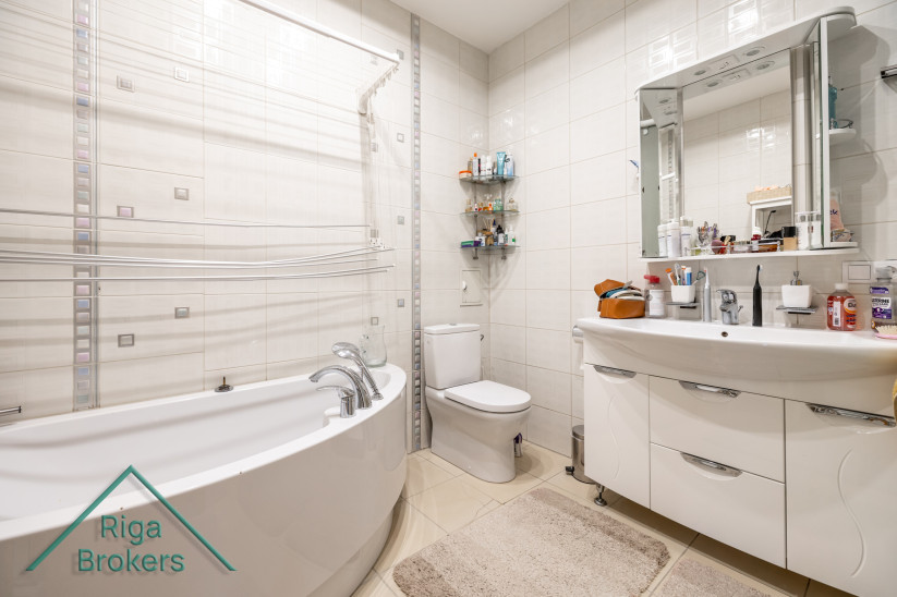Spacious bathroom with corner bathtub and mirror.