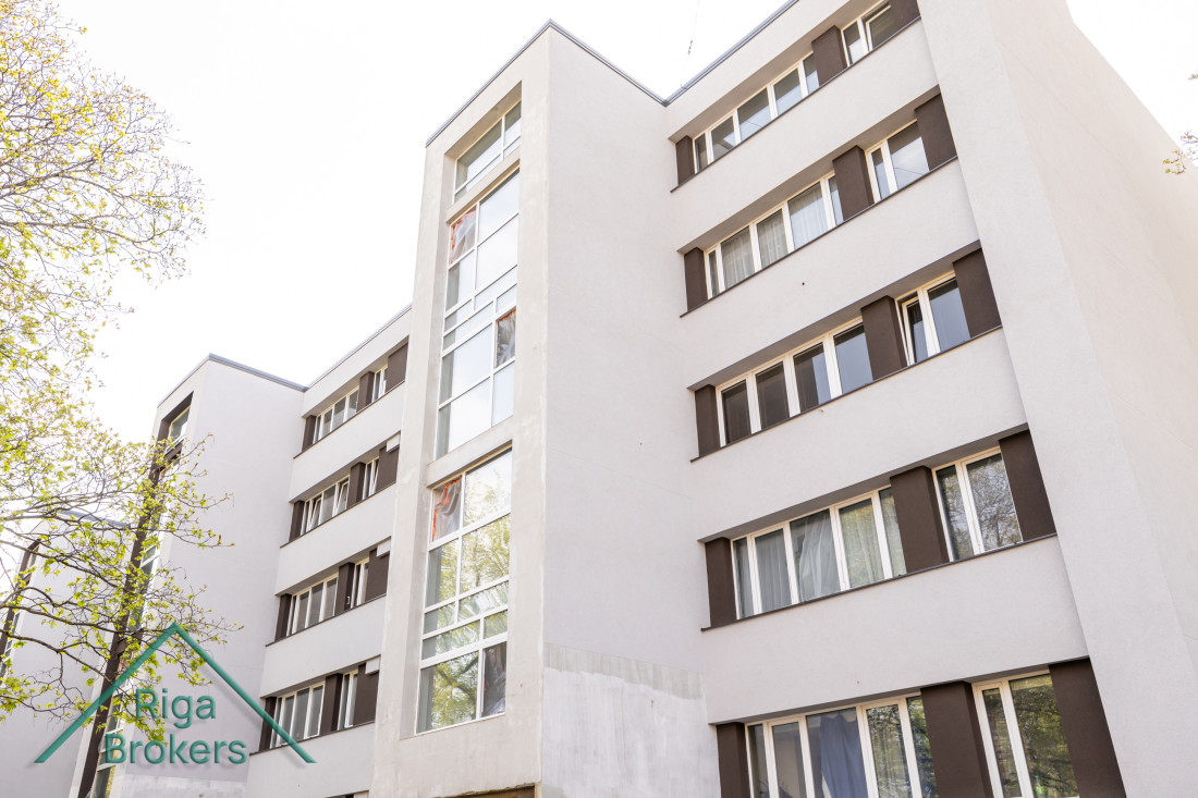 White multi-storey residential building with a logo. 