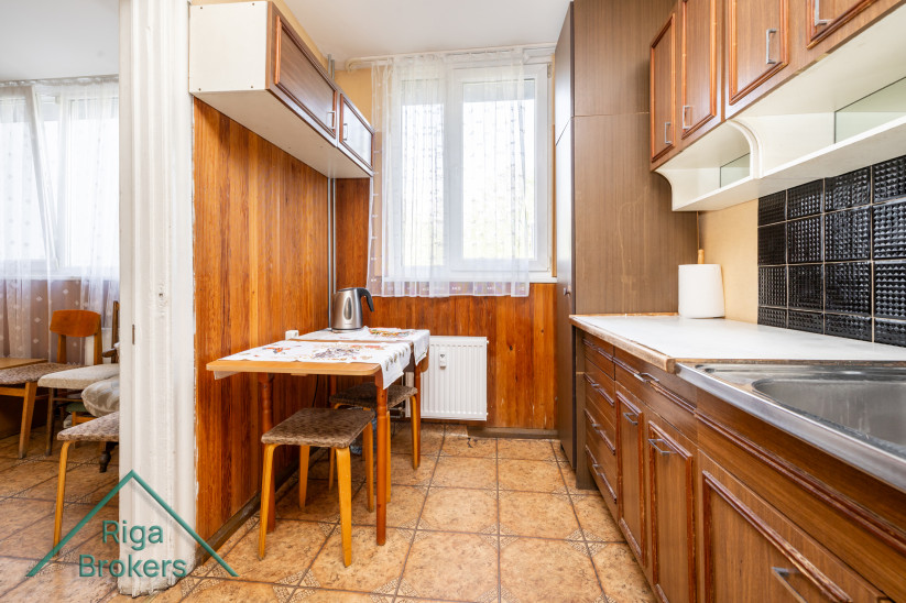 Kitchen with wooden furniture and a tablecloth. 