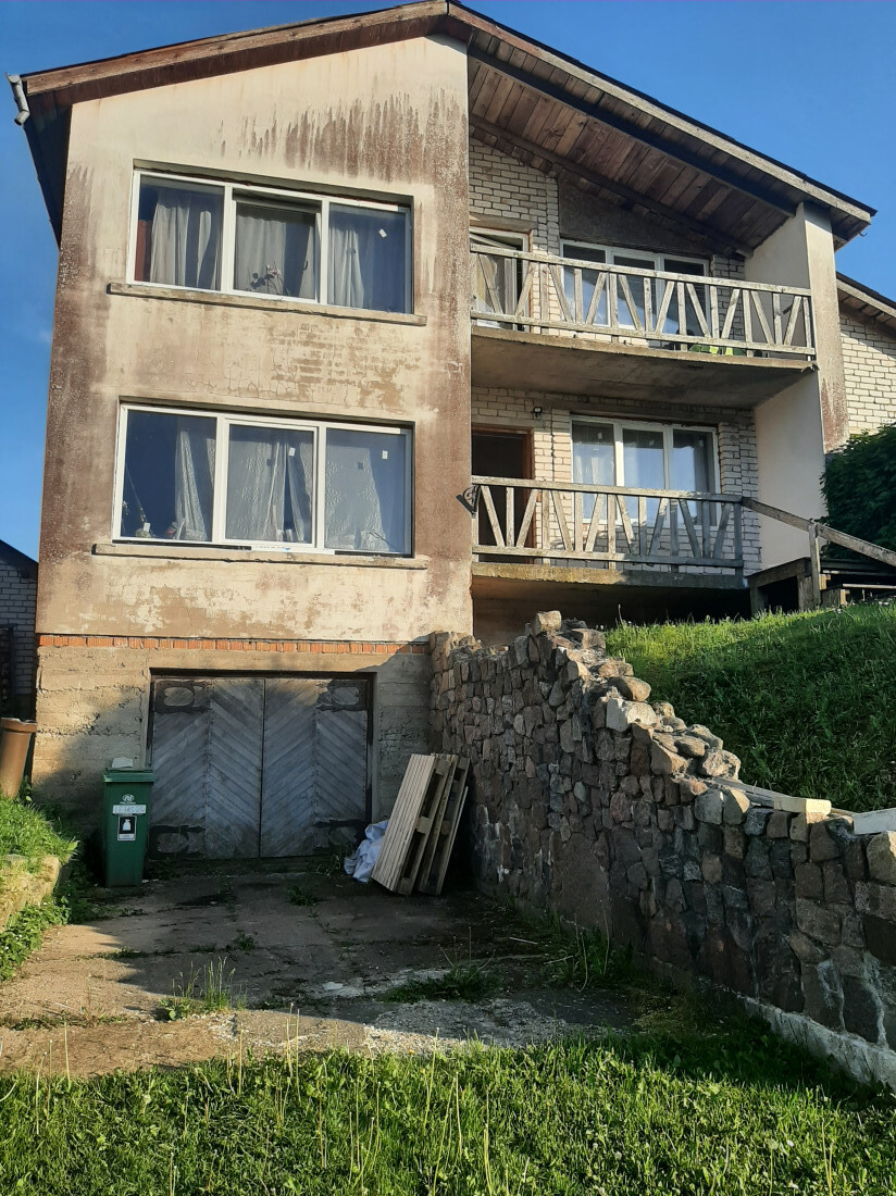 Two-story house with a basement and stone fence.