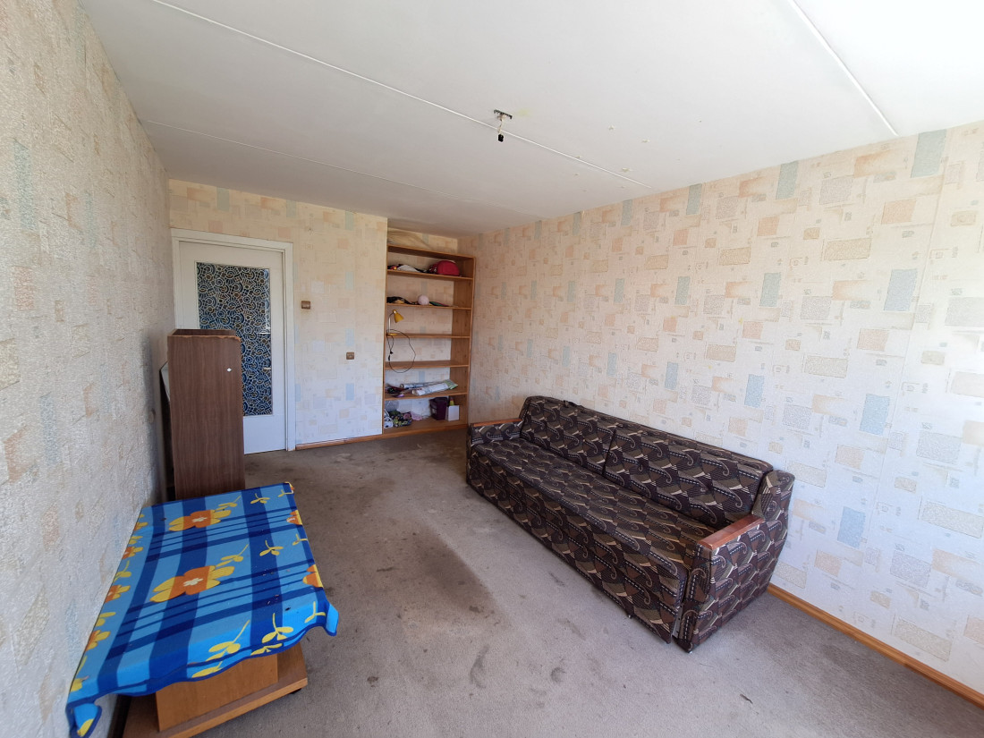 Room with sofa, shelf, and wallpaper.