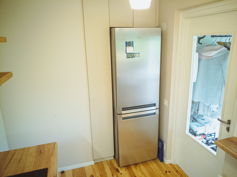 Refrigerator in the kitchen with white walls.