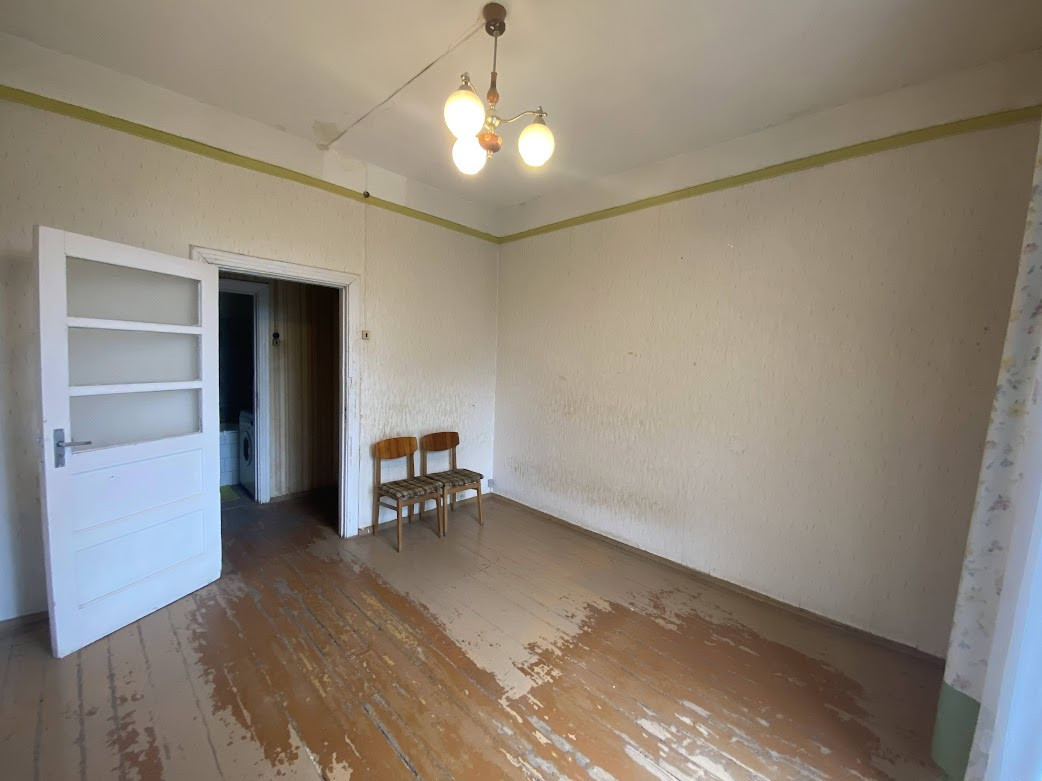 Empty room with wooden floor and two chairs.