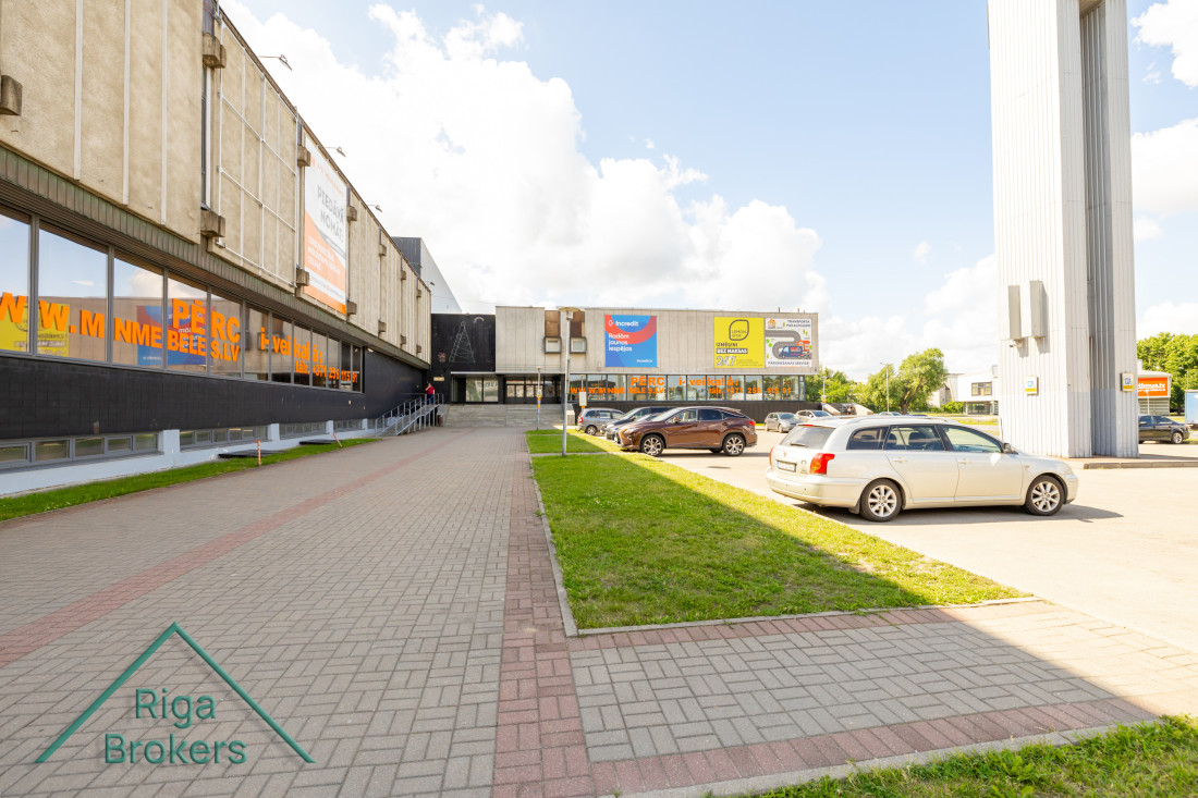 Mēbeļu nama ieeja ar automašīnām stāvvietā.