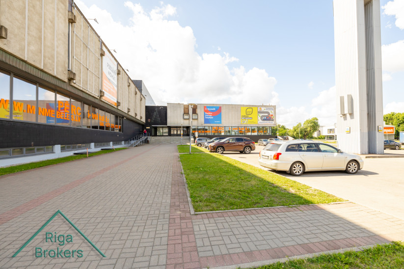 Mēbeļu nama ieeja ar automašīnām stāvvietā.