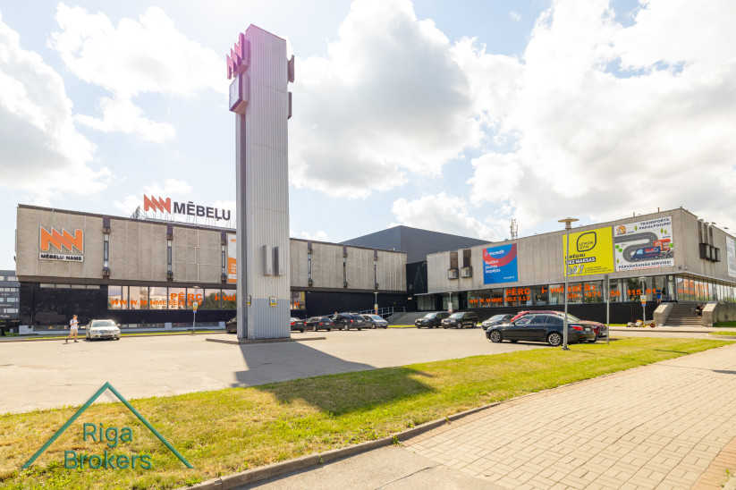 Mēbeļu nama ēka ar automašīnu stāvvietu.