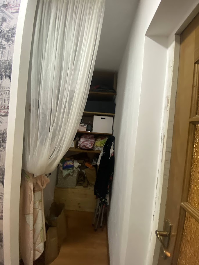 Šaurs koridors ar baltām sienām un dizaina elementiem.