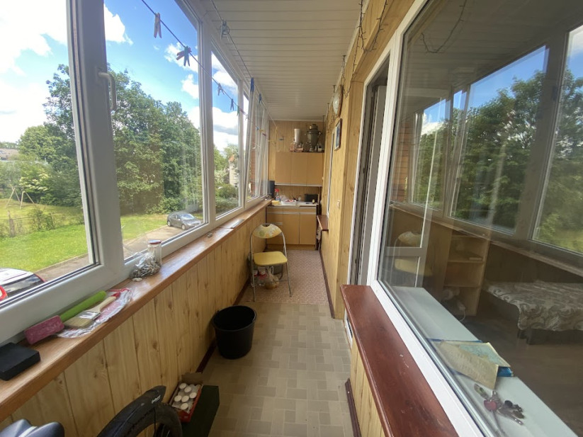 Veranda ar skatu uz zaļu dārzu un daudz logiem.