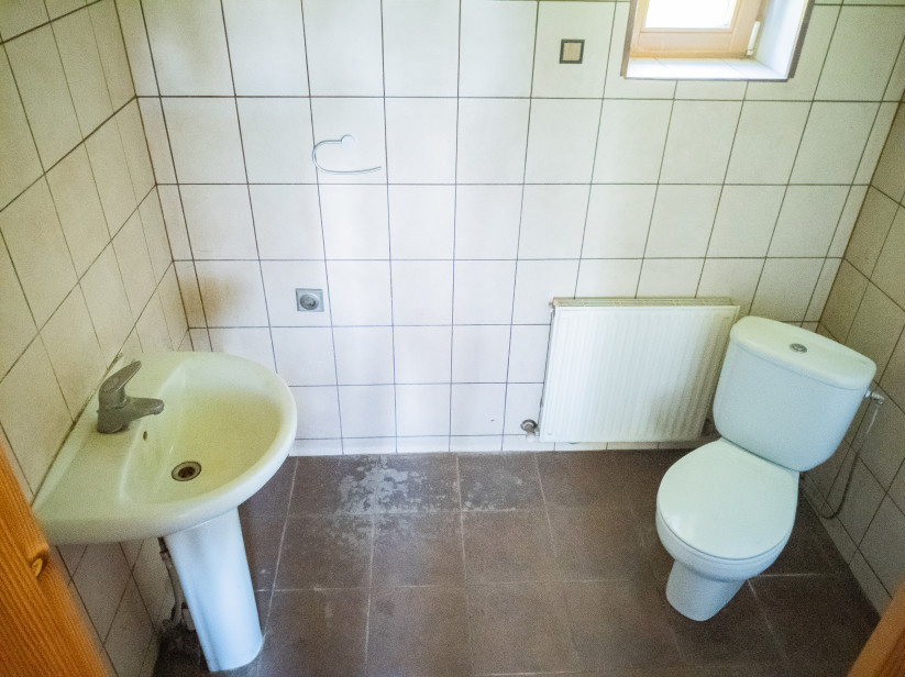 Flīzēta vannas istaba ar izlietni un tualeti.