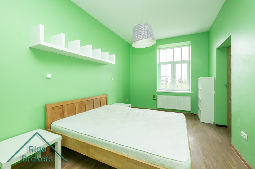  Green bedroom with a shelf and bed.