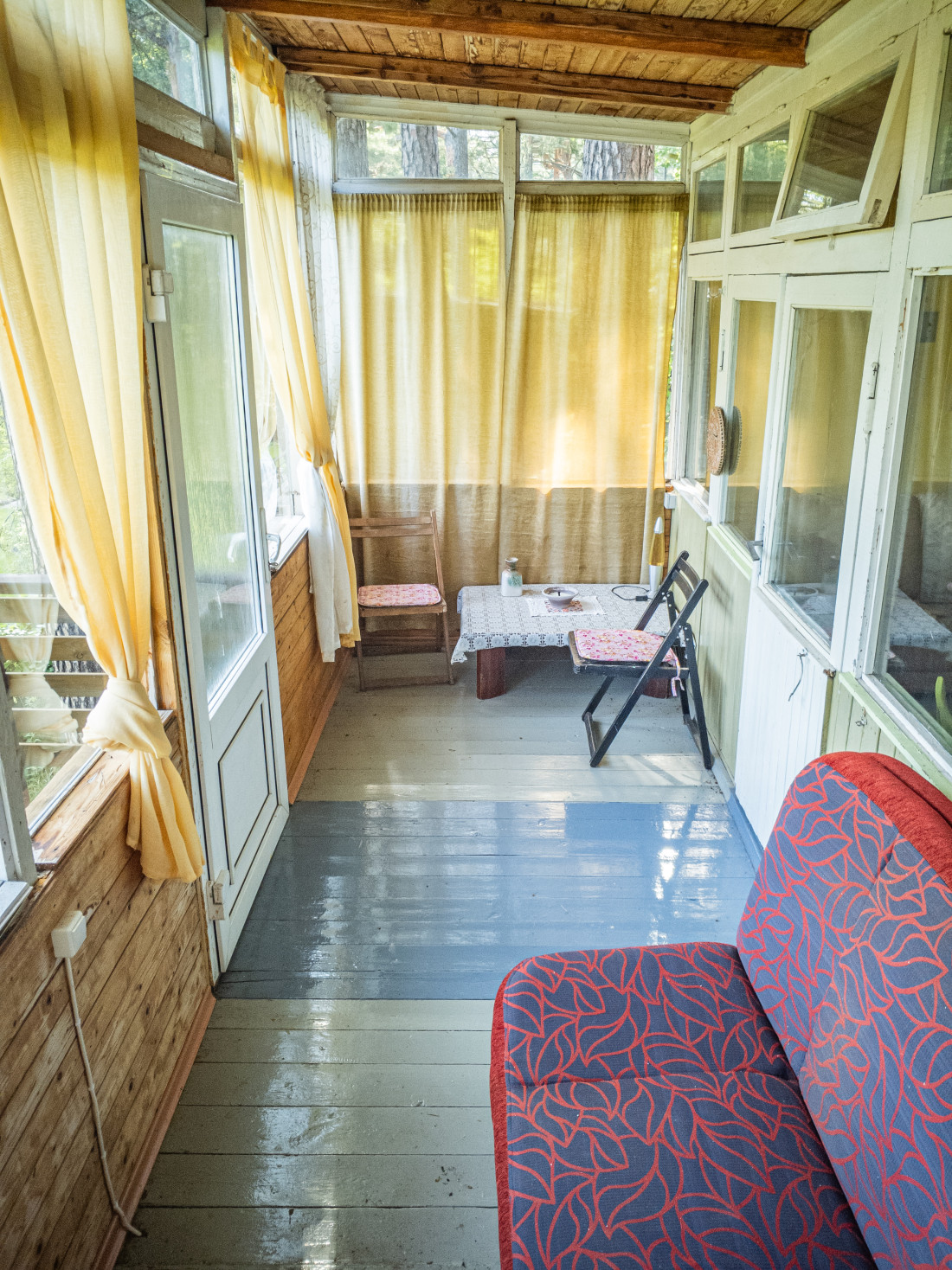 Stiklota veranda ar galdiņu un aizkariem.