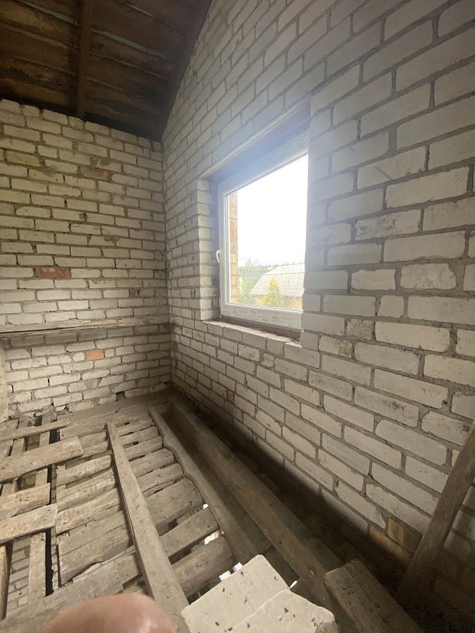 Window frame in an unfinished brick room.