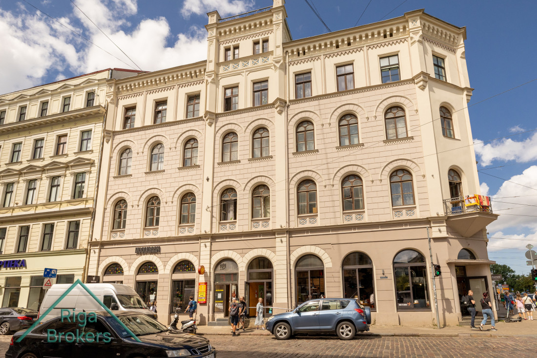 Baltas ēkas fasāde ar veikaliem pirmajā stāvā
