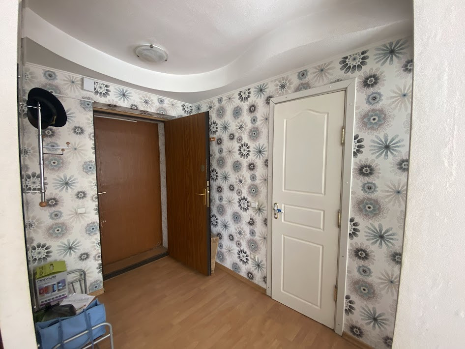 Hallway with patterned wallpaper and multiple doors.