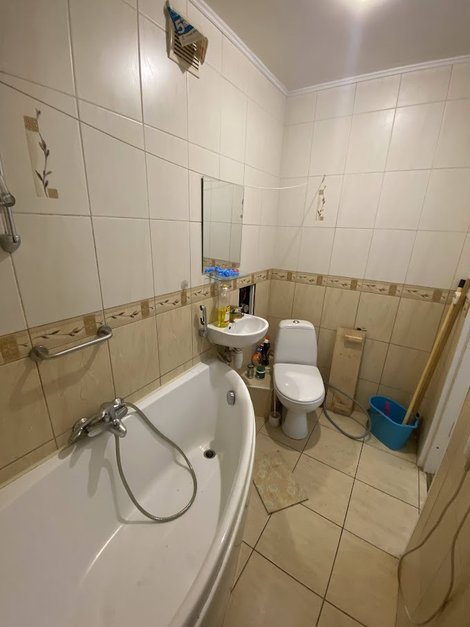 Bathroom with a bathtub and white tiled panels.