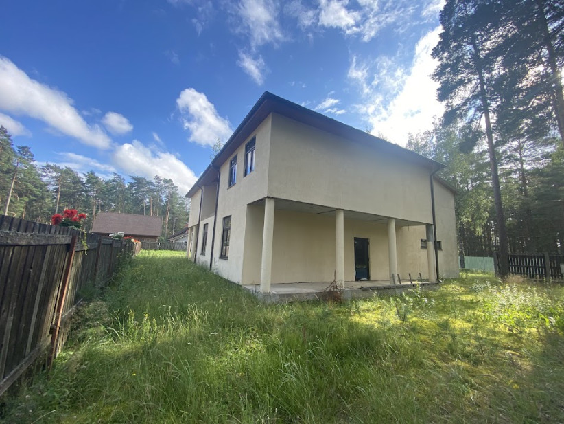 Divstāvu mājas sānskats ar zālāju.