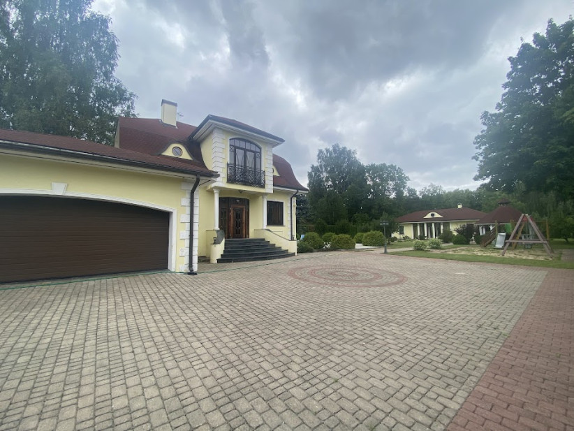Māja ar piebūvi un bērnu rotaļu laukumu.