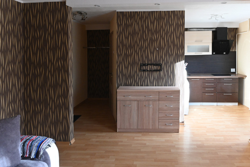 В квартире коричневые стены, комната объединена с кухонной зоной