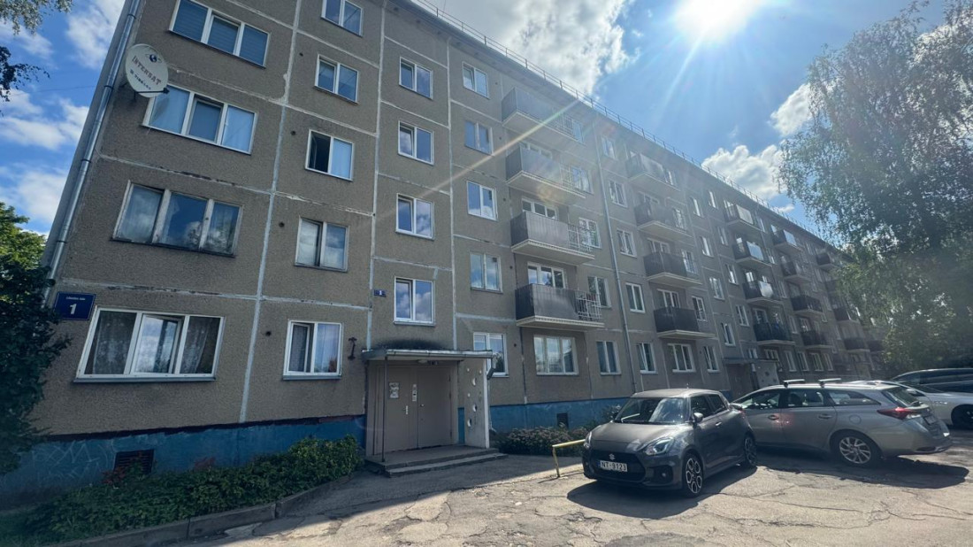 Piecstāvu daudzdzīvokļu ēka saulainā dienā.