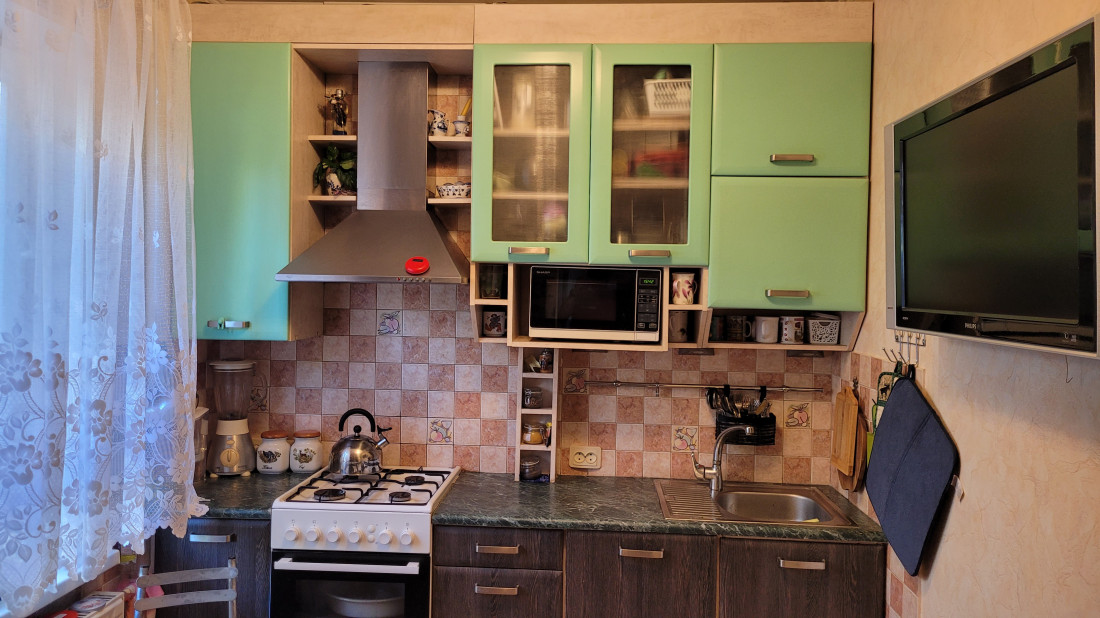 Kitchen with green cabinets and stove.